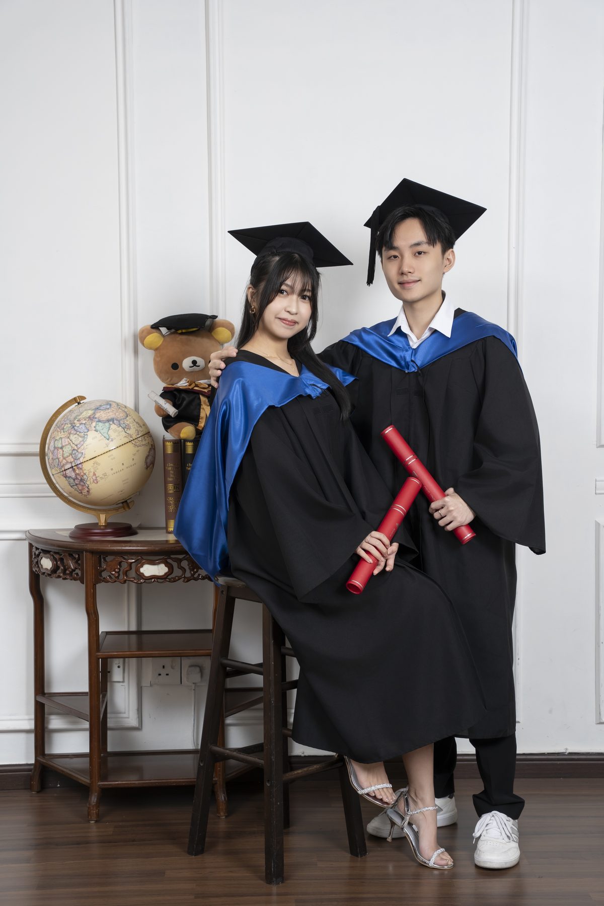 Premo Studio real client graduation photo — graduate with parents, studio backdrop